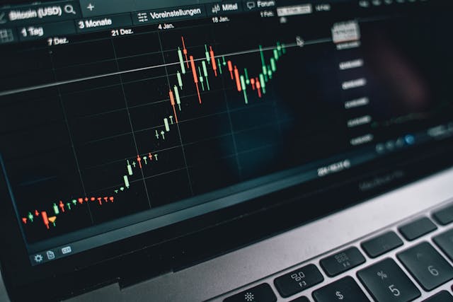 Close-up of a laptop screen displaying a stock market candlestick chart with a rising price trend